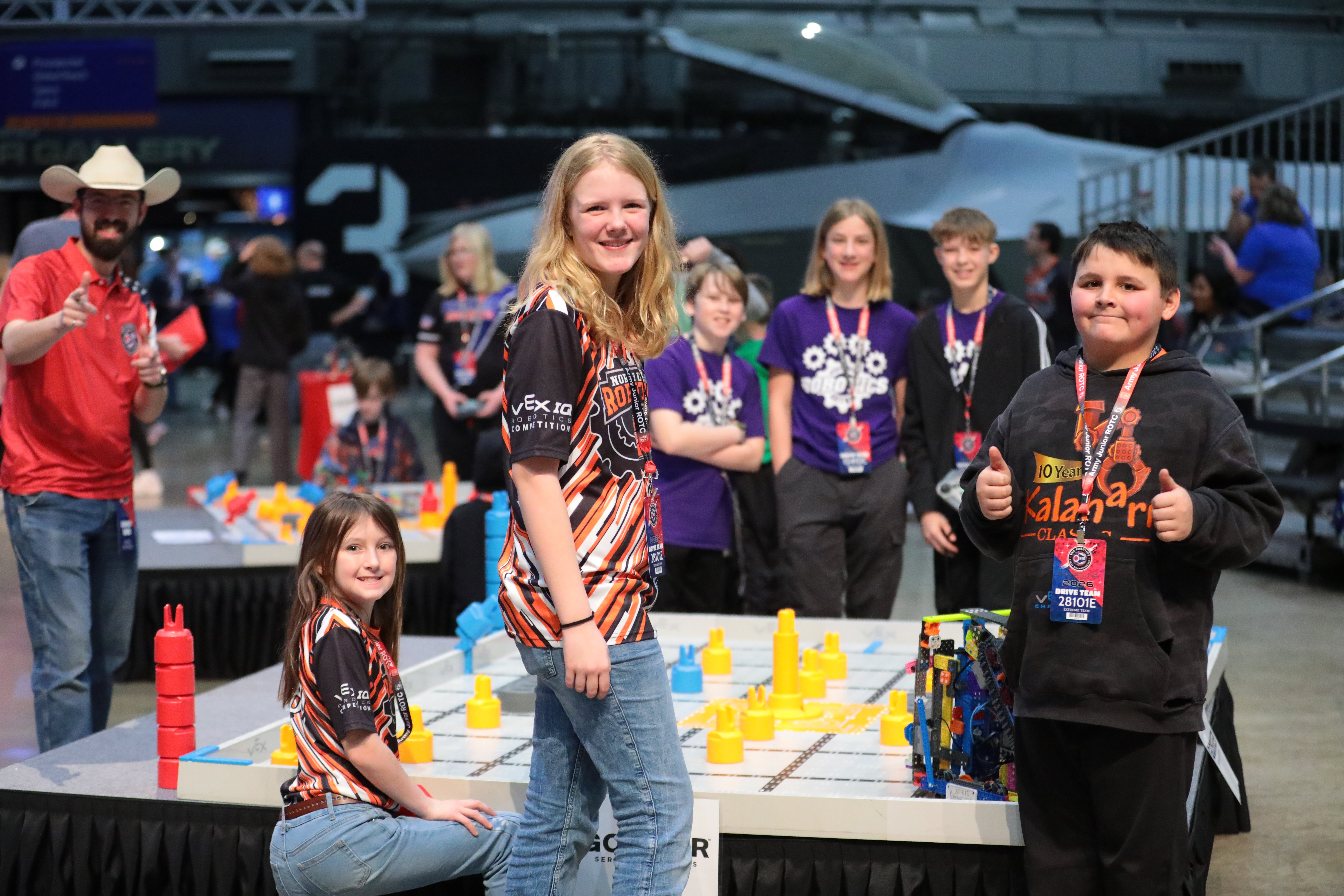 Two teams pose around an IQ field before a match begins. A referee can be seen to the side of the field as well.