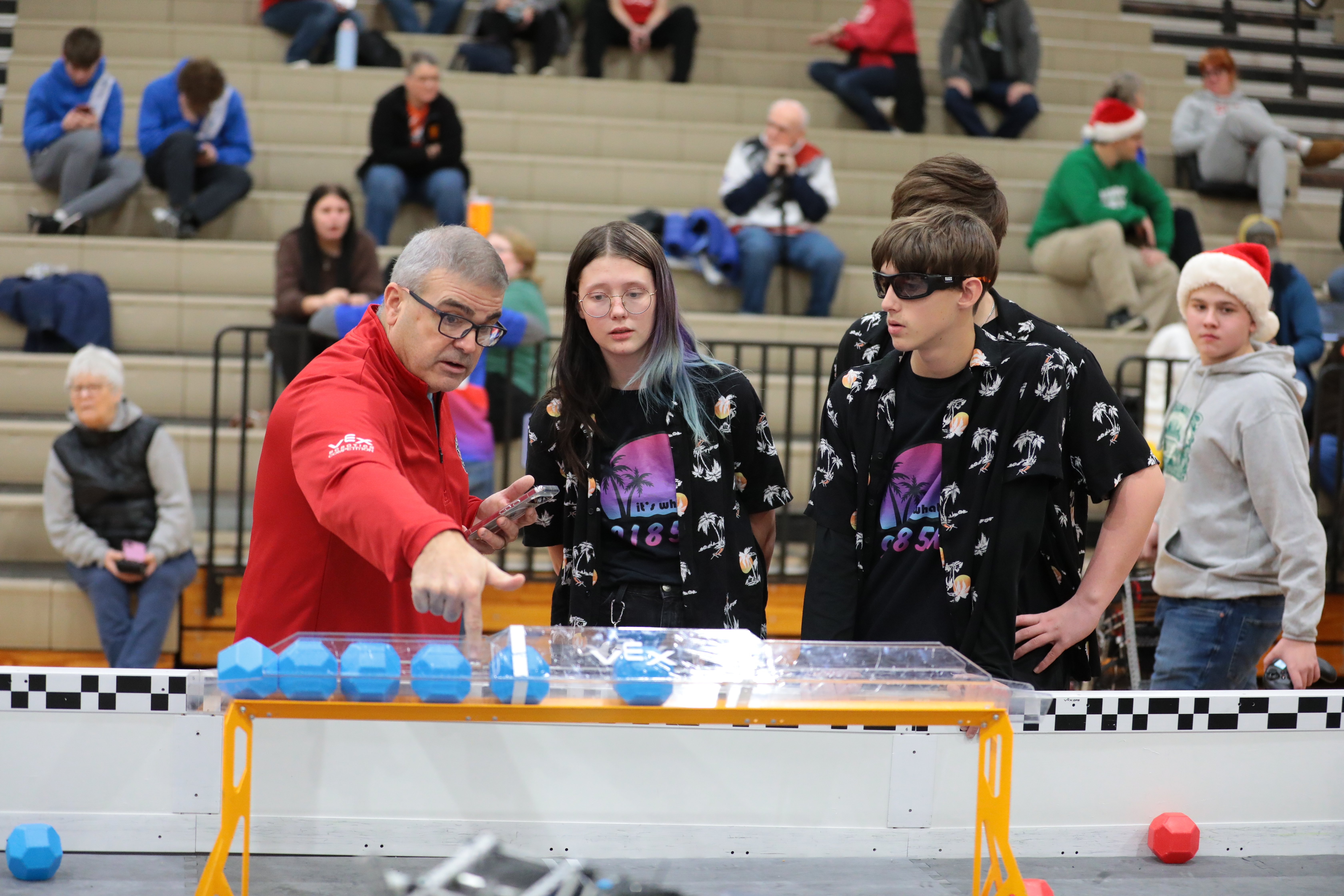 A head referee talks with a team beside a field, pointing at the robot and scoring objects at the end of the match.