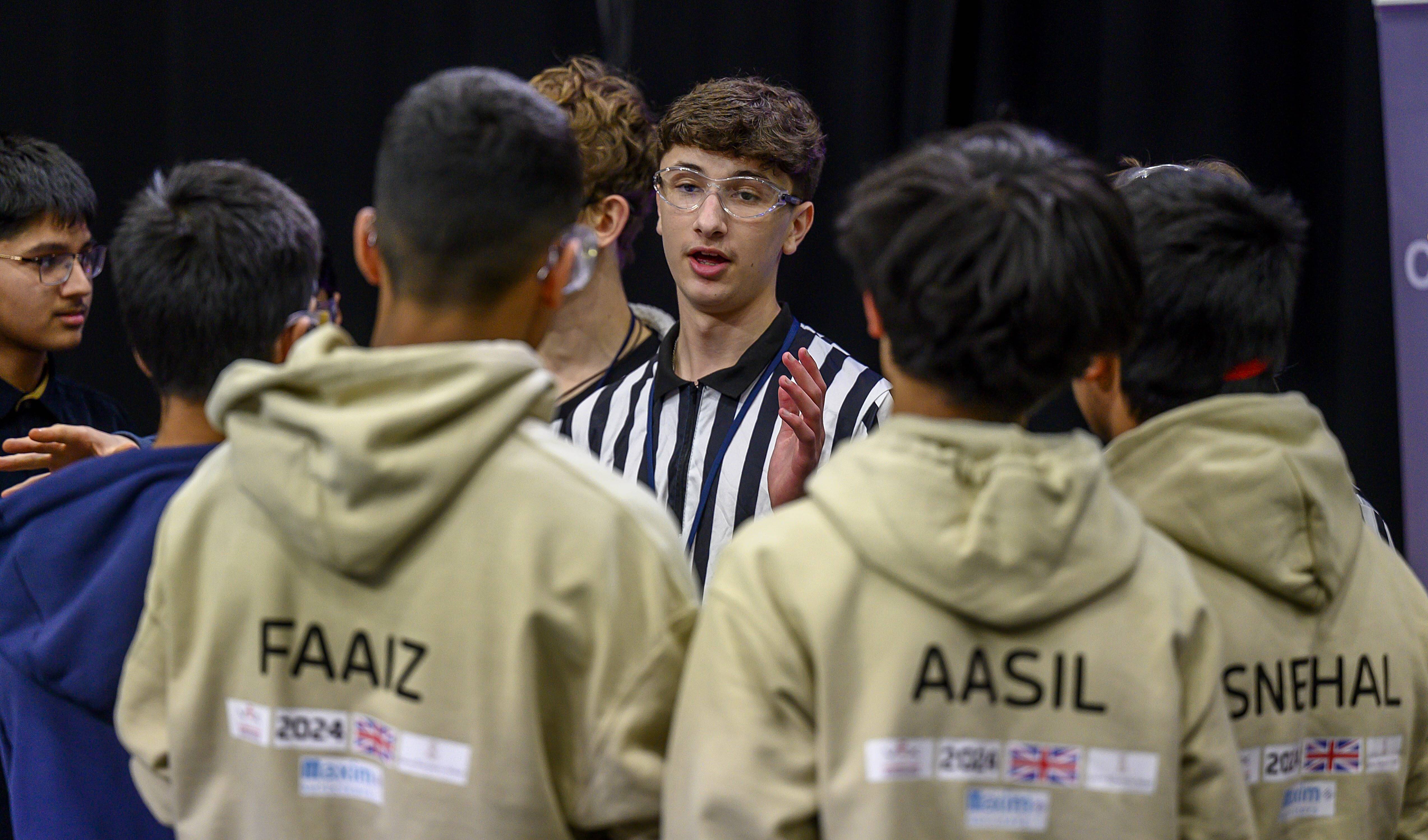 A referee stands and talks to an alliance after a match.