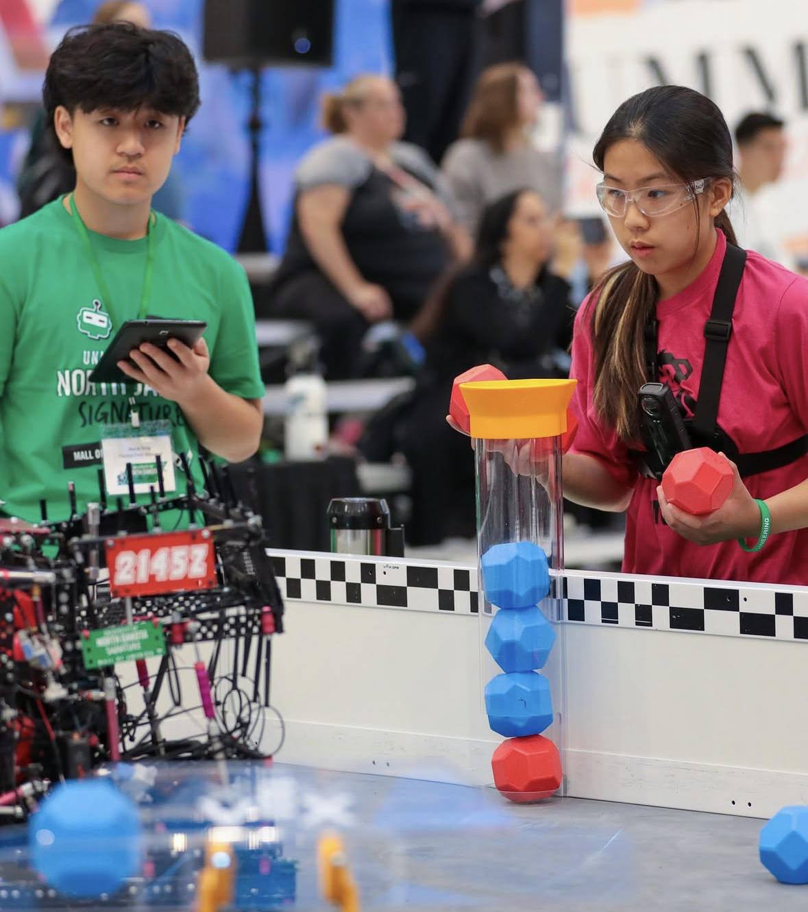 A referee looking on at a match while a team member match loads the robot.