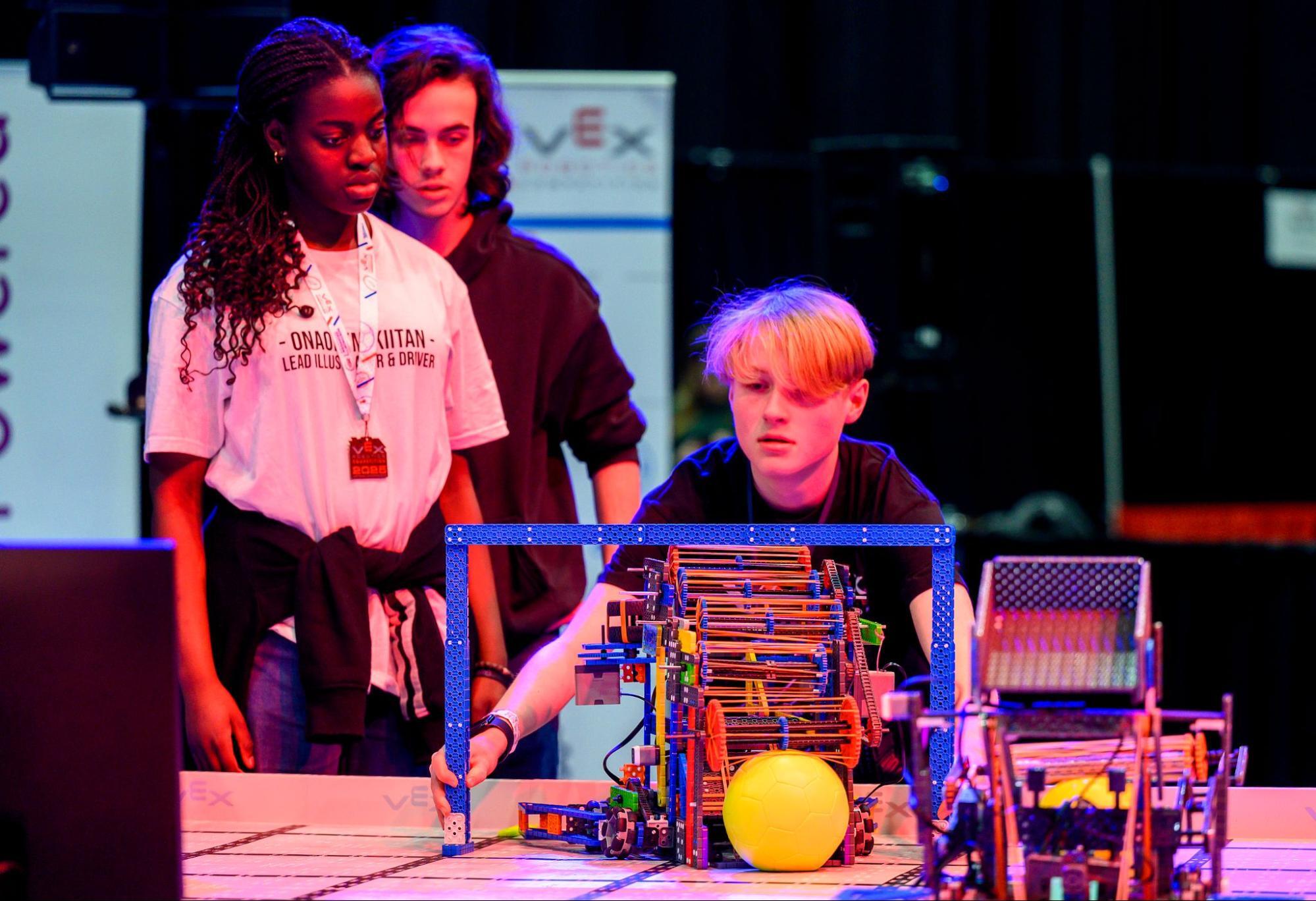 An inspector runs a sizing tool over a robot to see if it meets inspection criteria.
