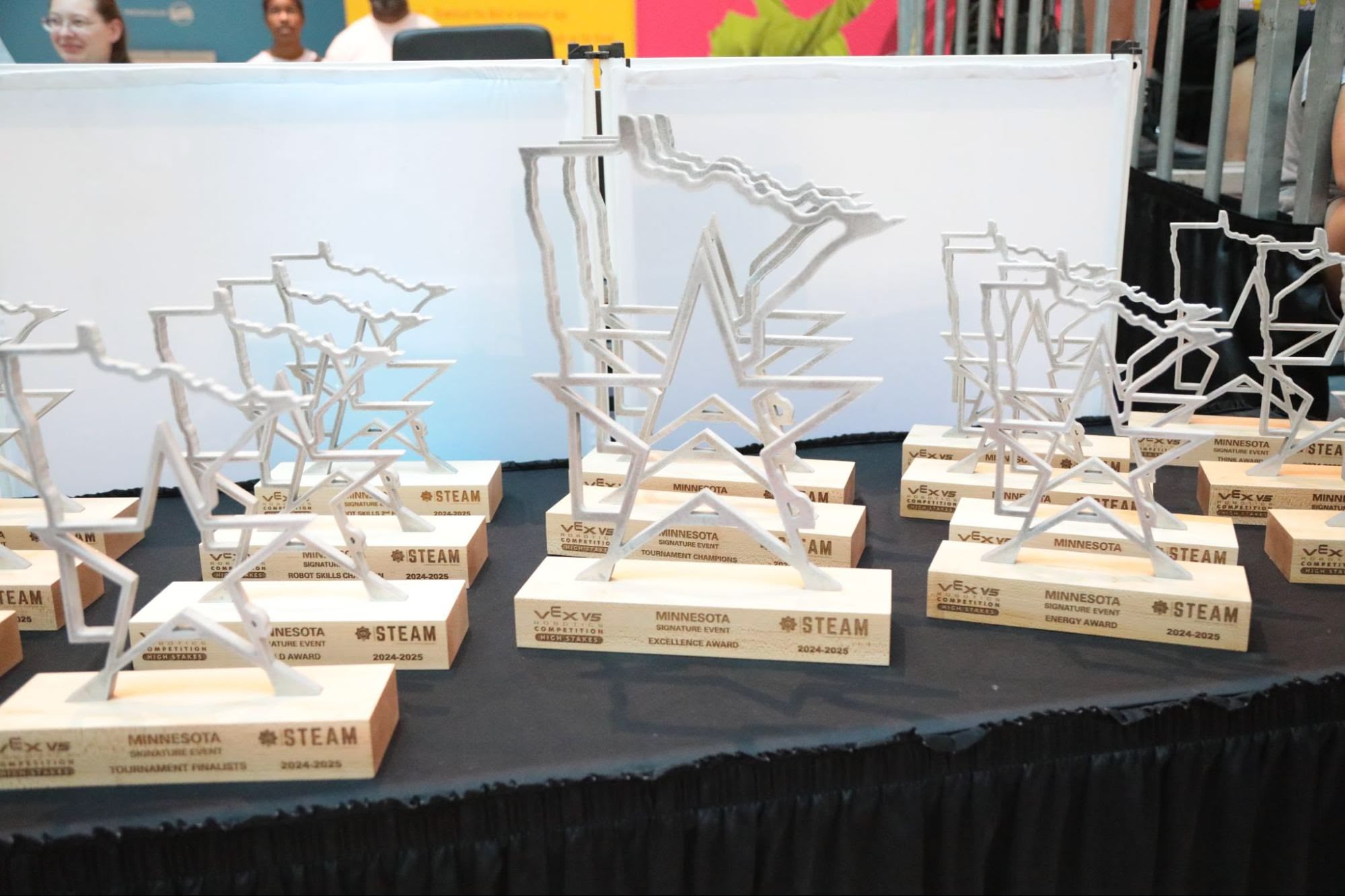 A table at an event with a series of trophies for all awards, including Excellence Award, Tournament Champion, and others.