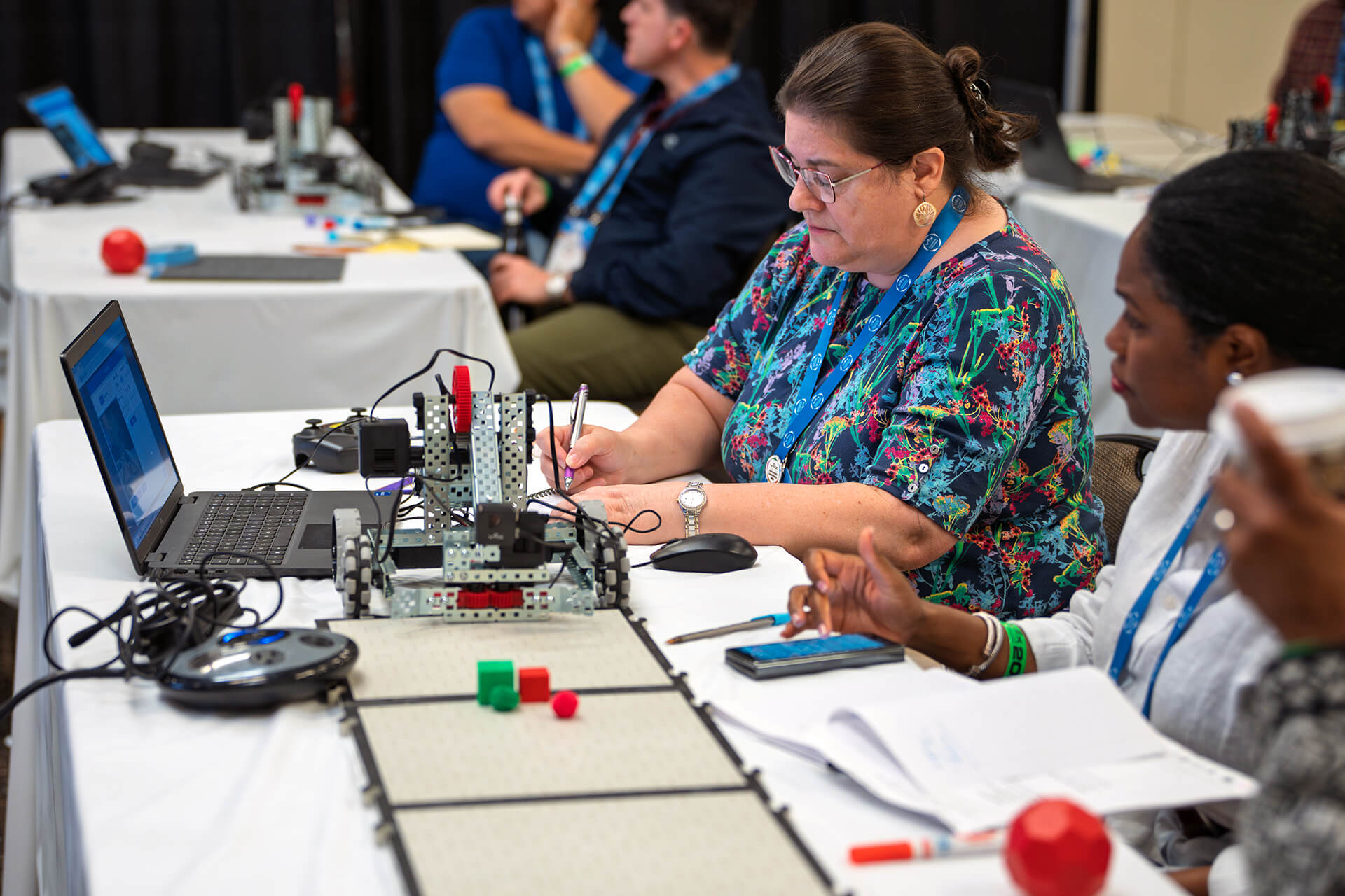 Workshop attendees working together with laptops and VEX materials.